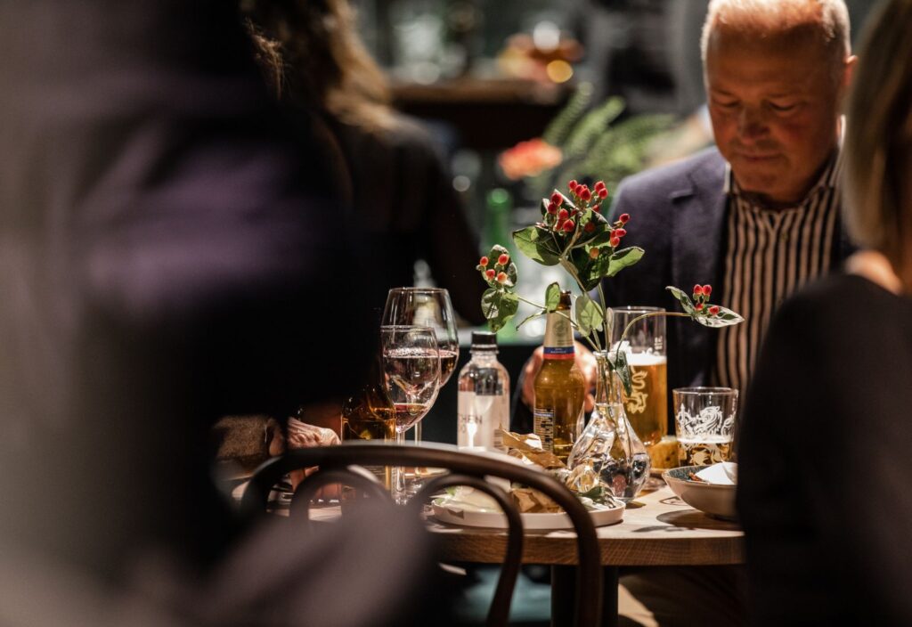 Ett bord på en restaurang med tallrikar och glas. På ena sidan av bordet ser man en man som äter.