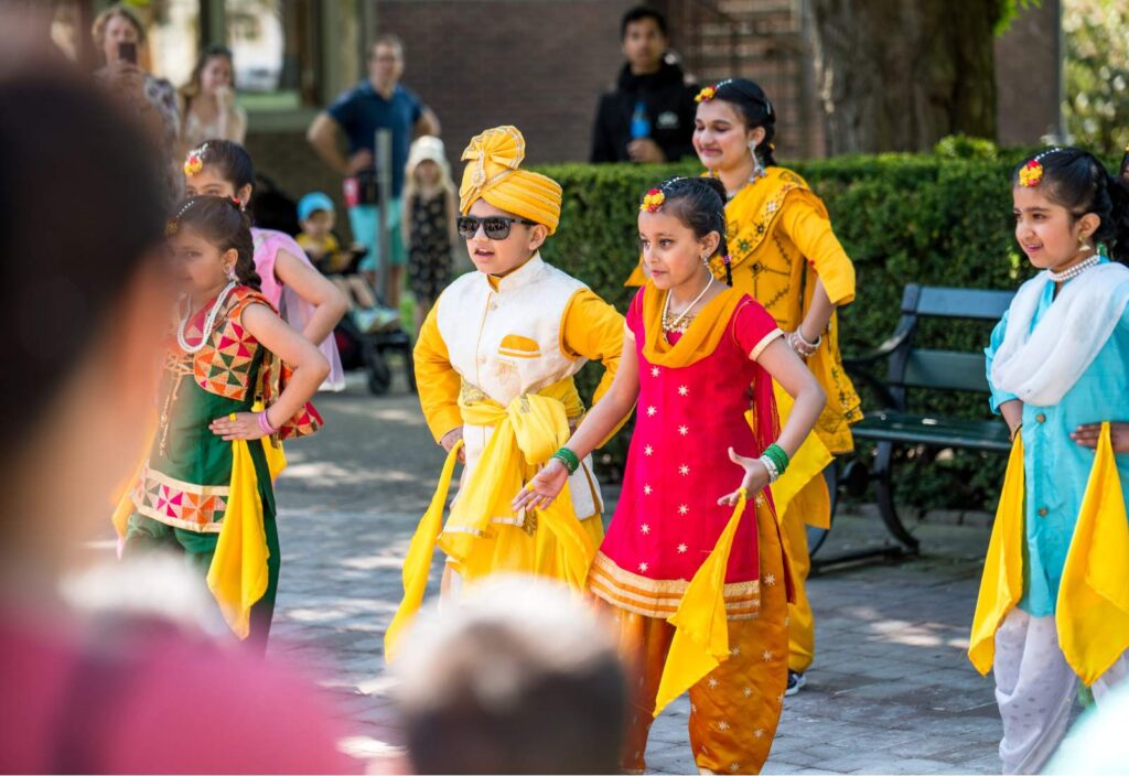 Barn i fina färgglada kläder som har dansuppträdande utomhus.