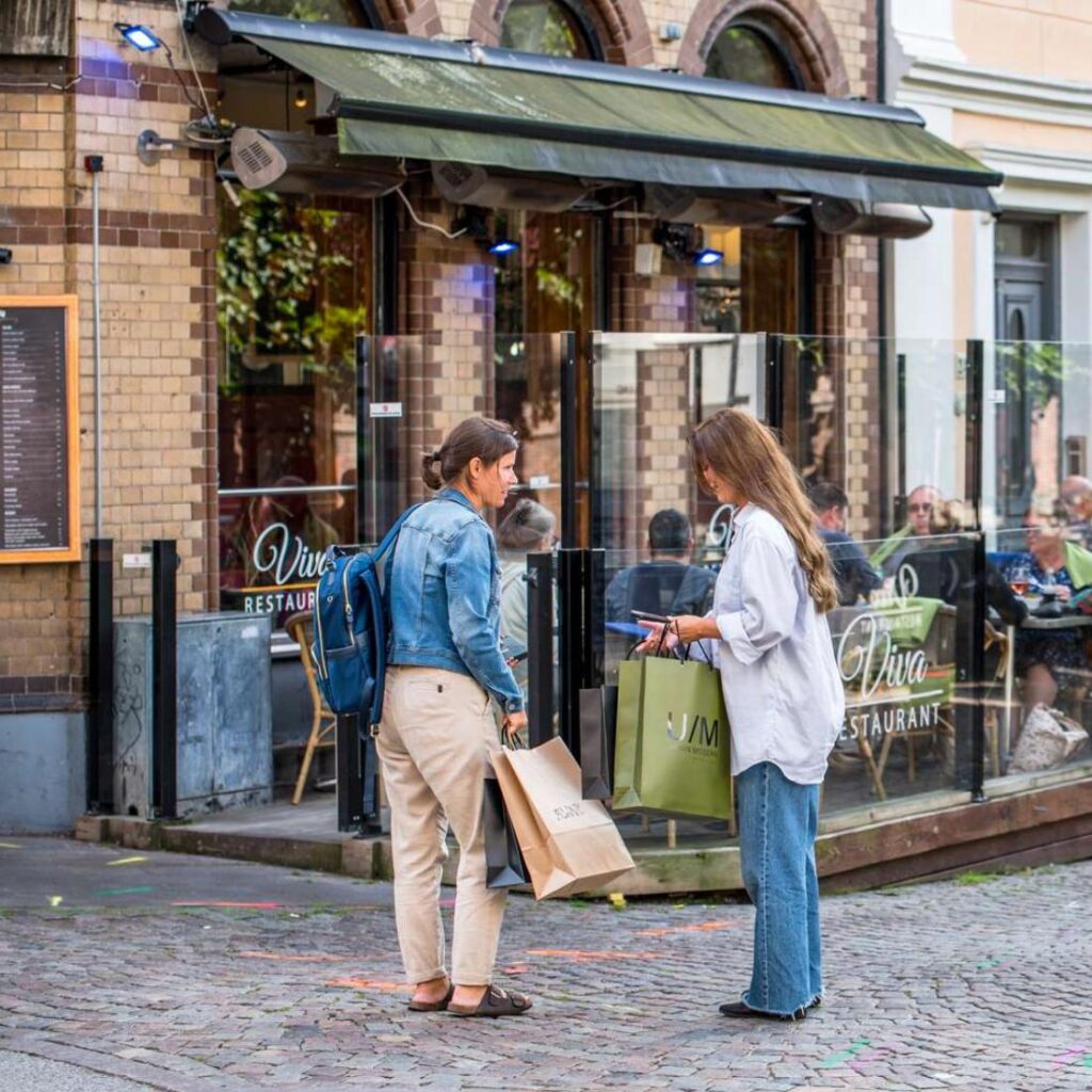 två kvinnor som håller i shoppingpåsar och står utanför en restaurang i stadskärnan