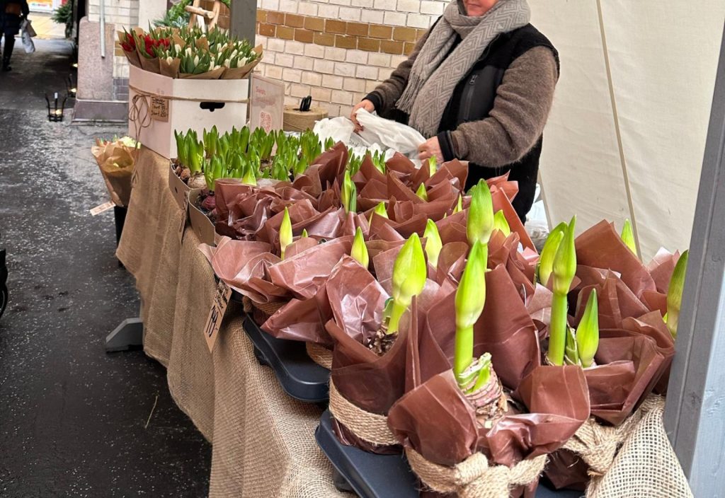 Det är ett marknadsstånd utomhus, där det är försäljning av blommor.