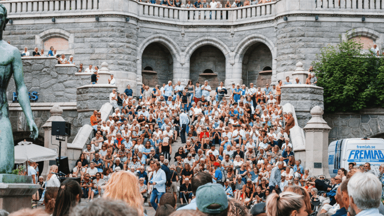Massor av människor sitter på trapporna till Terrasstrapporna i Helsingborg, framför står det en publik och tittar på en man som håller i en mikrofon