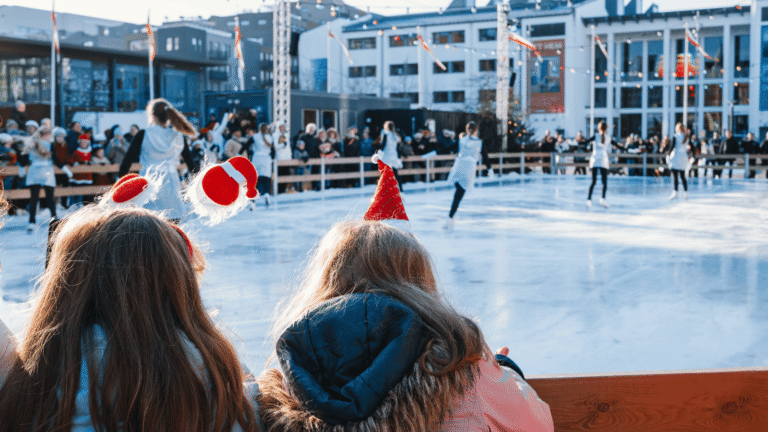 Två barn står med tomte-diadem och tittar ut över en utomhus-skridskobana