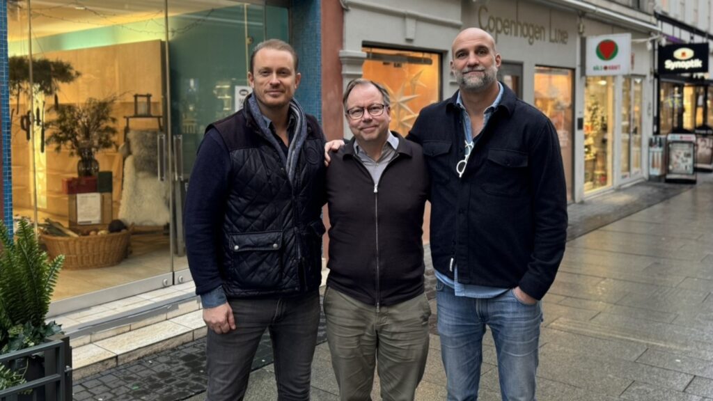 Tre män står framför ett skyltfönster.