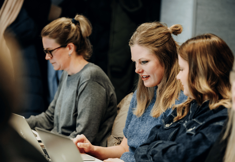 Tre kvinnor sitter med laptops framför sig