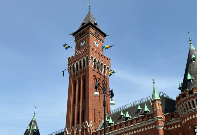 Rådhuset i Helsingborg och Sveriges flaggor som viftar med blå himmel bakom.