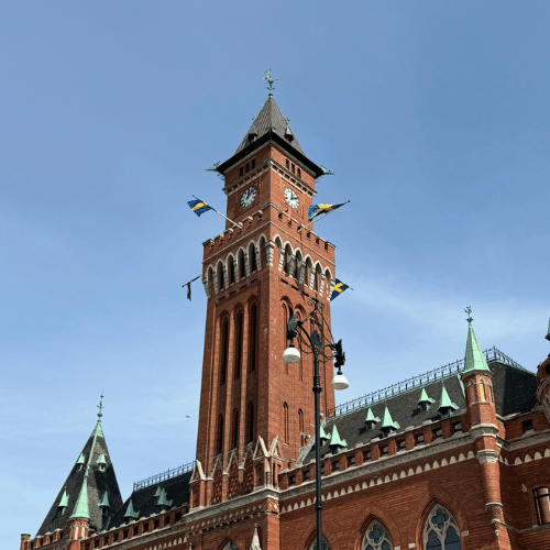 Helsingborgs Rådhus med vajande svenska flaggor och en blå himmel