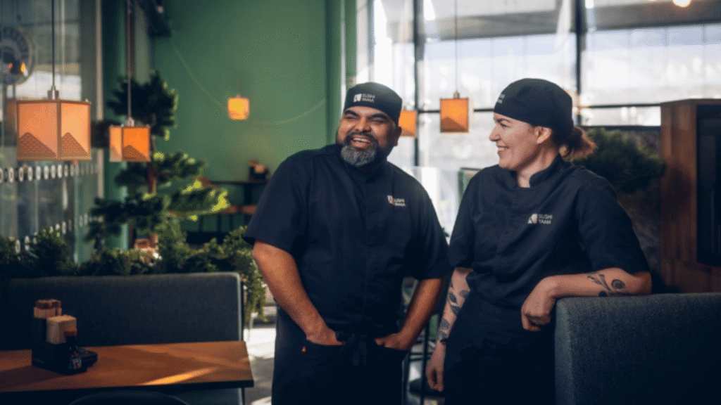 En man och en kvinna i svarta kockkläder står i en restaurang.