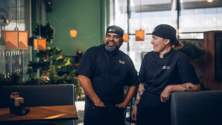 En man och en kvinna i svarta kockkläder står i en restaurang. 