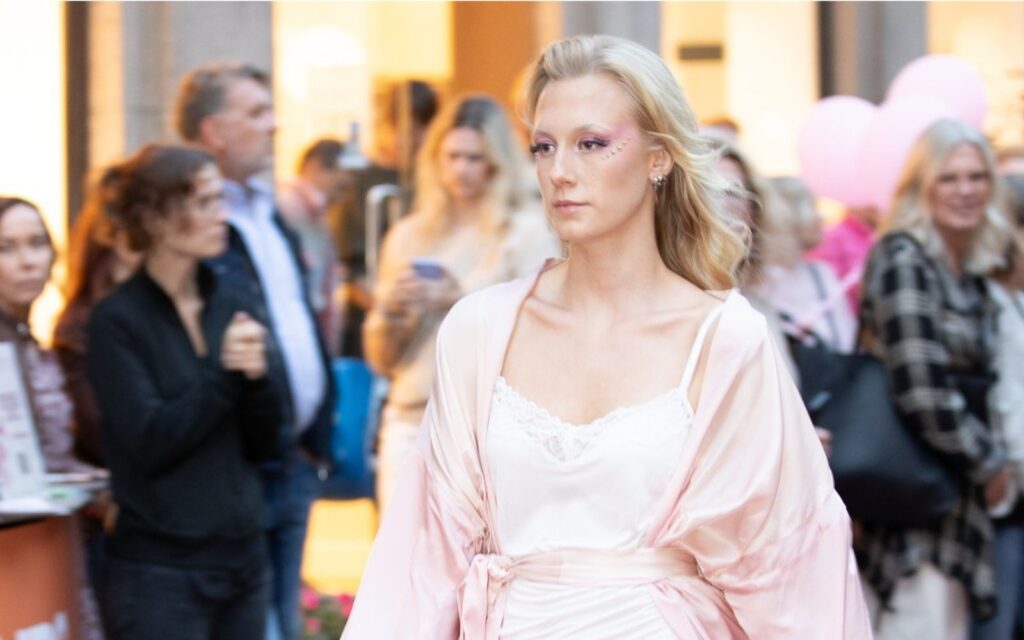 En tjej som har rosa kläder på sig och går i en catwalk utomhus